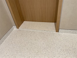 Corner of the terrazzo floor by a wood-clad wall in Rezidence Churchill