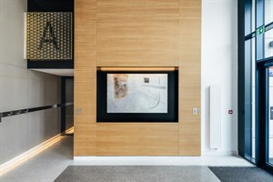 Eingebauter Kamin in einer holzverkleideten Wand in der Lobby von Rezidence Churchill