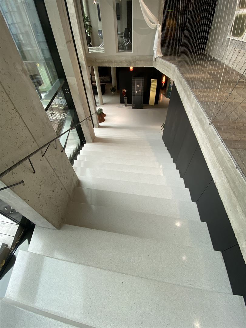 Terrazzotreppe in einer Galerie mit Skulpturen und Pflanzen unten