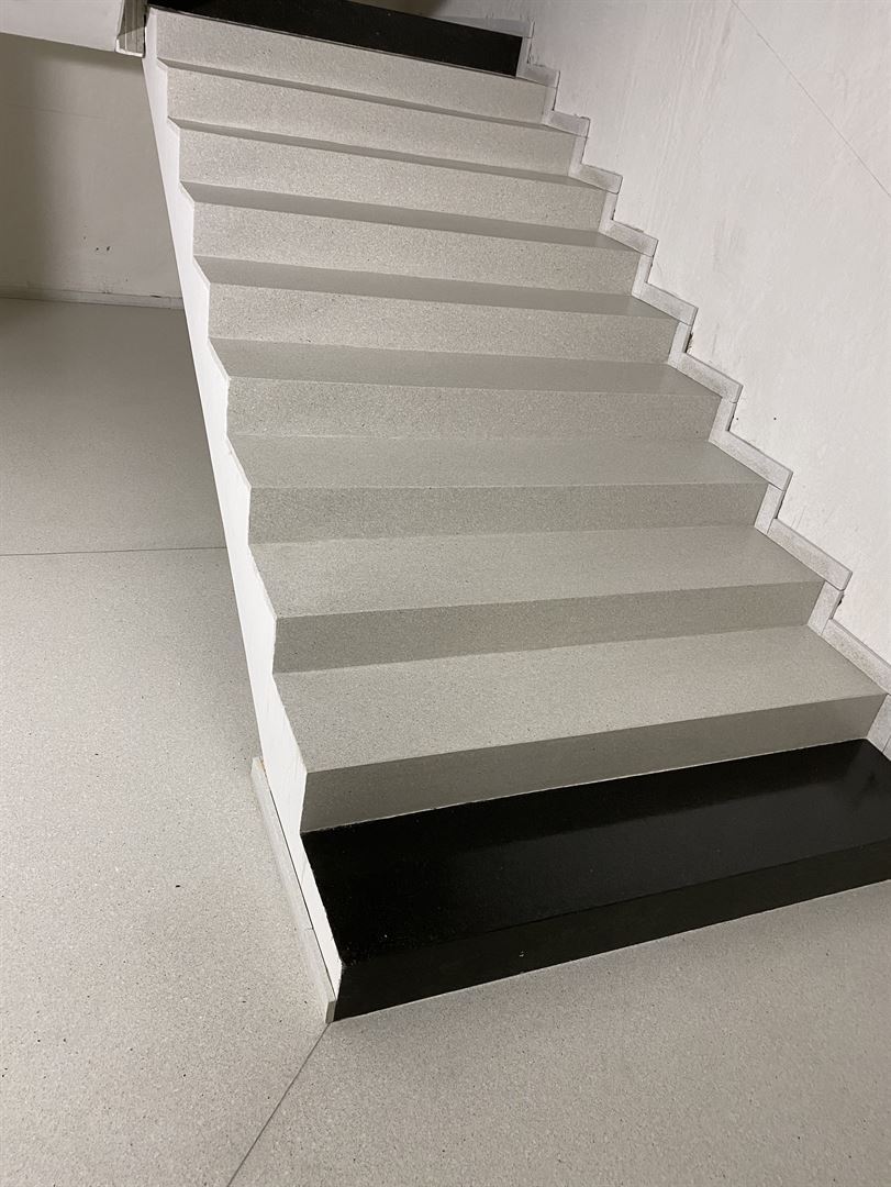 Terrazzotreppe mit hellen Stufen und schwarzem Sockel am Fuß