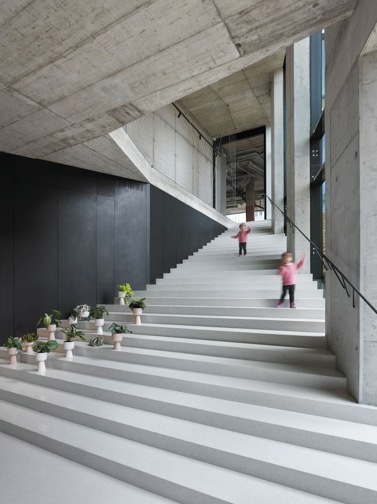 Terrazzotreppe von oben neben Glasbrüstung und dunkler Wandverkleidung