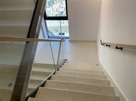 Treppe mit Terrazzostufen und Glasgeländer in Rezidence Churchill