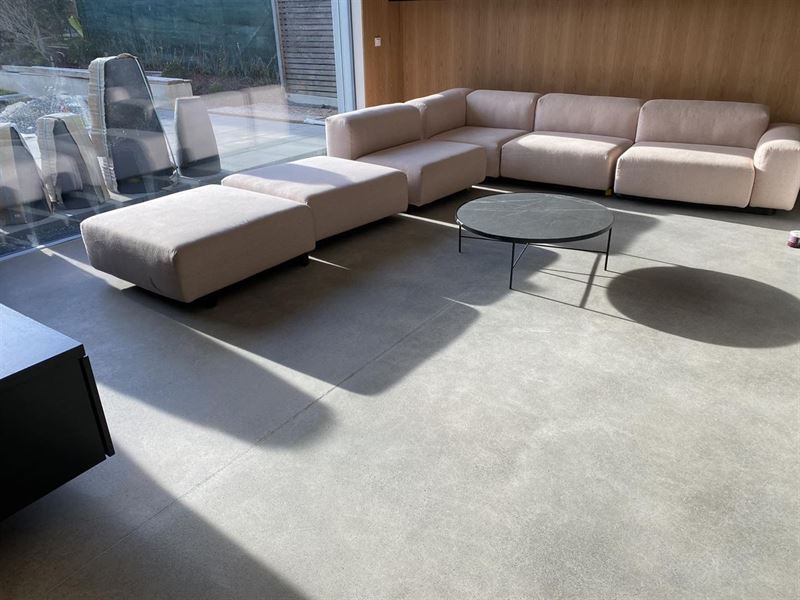 Wohnbereich mit glattem Betonboden und großem Sofa