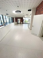 Geräumige Schulhalle mit Terrazzoboden und Ziegelwand