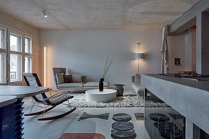 Wohnbereich der Wohnung Ovenecká mit Schaukelstuhl und Betonkücheninsel