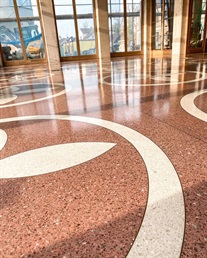 Detail červené terrazzo podlahy s krémovým květinovým ornamentem