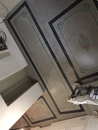 Tmavé ornamentální pásy v lité podlaze a bruska při broušení