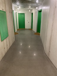 Chodba s betonovou podlahou a zelenými dveřmi