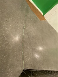 Detail betonové podlahy u zelených dveří